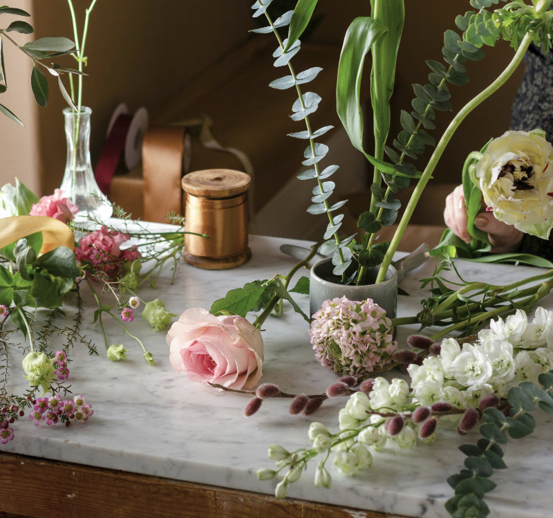 Floristik-Arbeitsplatz mit rosa Rose, Eukalyptus, Hortensie und weißen Blüten auf einer Marmorplatte – Floristik NaturTraum