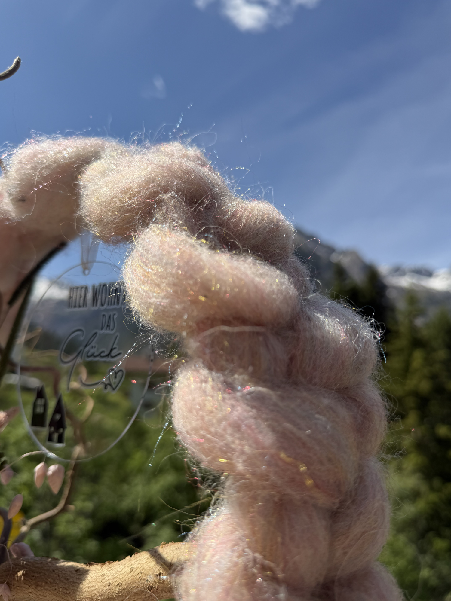 Extreme Nahaufnahme rosafarbene Wolle mit Glitzereinlage im Sonnenlicht vor Lechtaler Bergpanorama – Naturmaterial Wollkranz NaturTraum